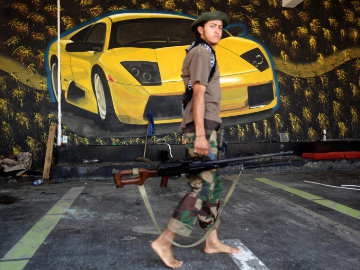 Rebelde armado passa diante de uma pintura de uma Lamborgini na casa de veraneio de Saadi Gaddaafi