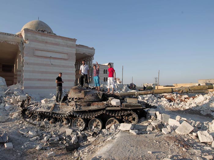 Crianças sírias brincam em cima de tanque de guerra destruído, em Aleppo (AFP PHOTO/AHMAD GHARABLI) posam sobre tanque